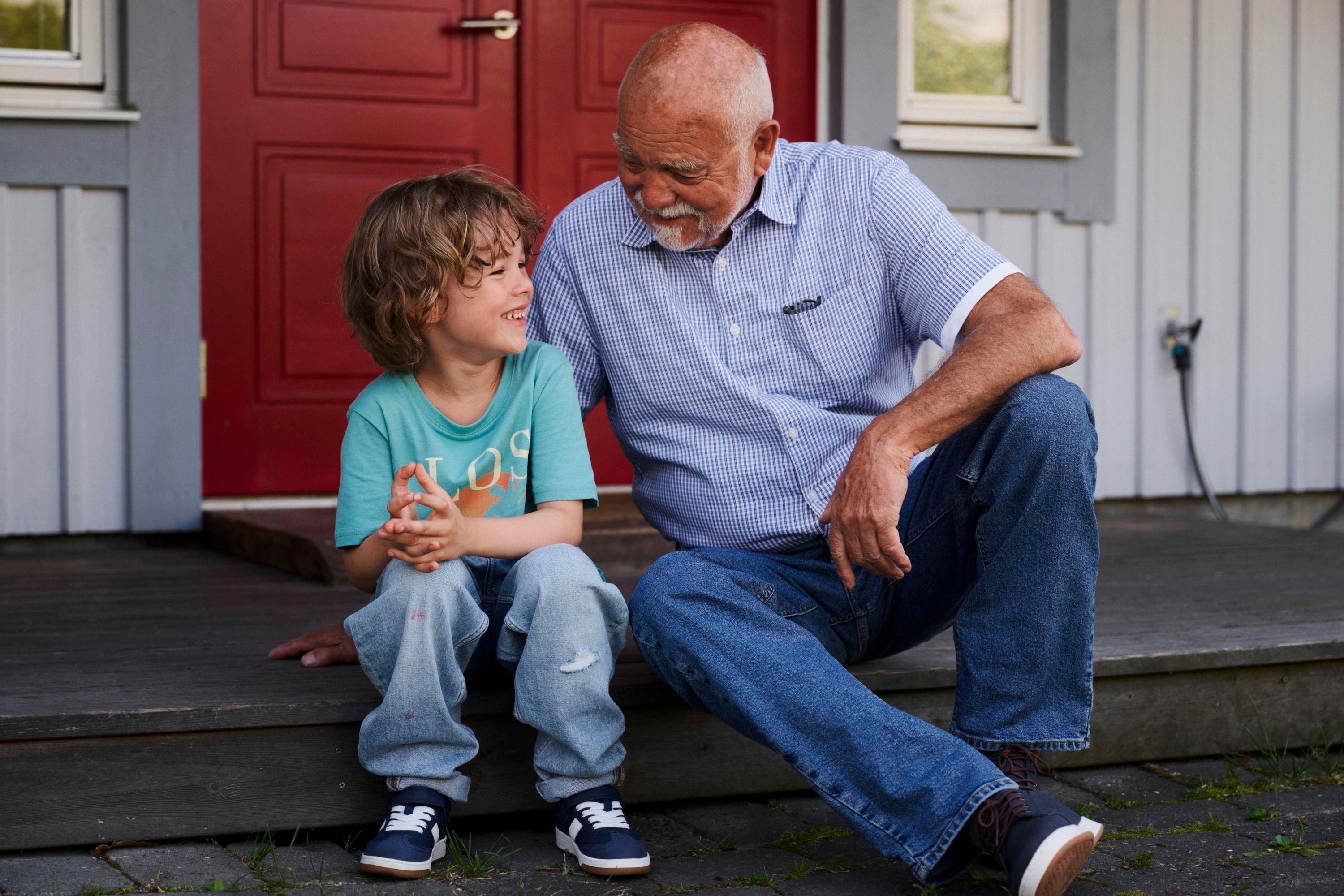 A child and an older man sitting on a staircase having a chat